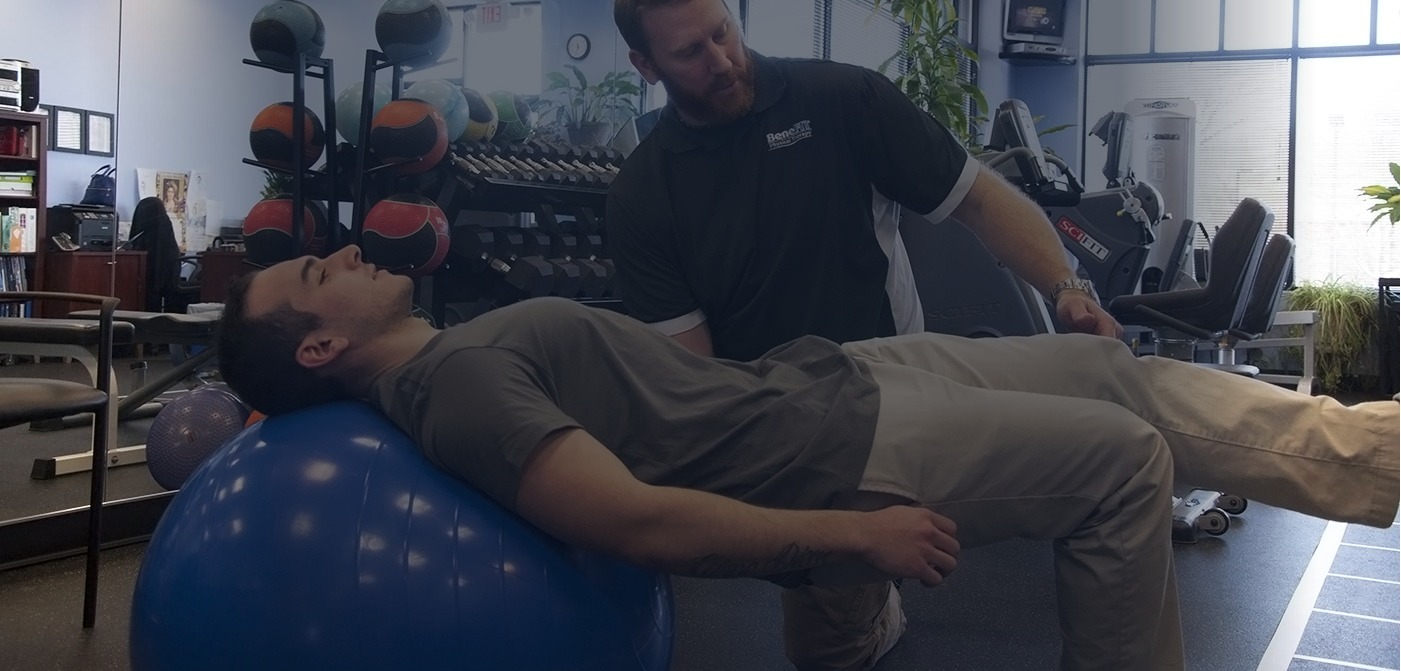 Physical therapist guiding a patient through a therapeutic exercise on a stability ball at BeneFIT Physical Therapy in Bridgewater, NJ